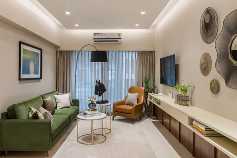 Living room in a Mumbai two-bedroom show apartment with a green three-seat sofa, a mustard chair and slim wall-mounted TV storage