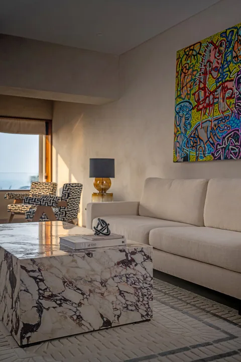 A South Mumbai apartment living room with a veined-marble coffee table, ivory upholstery and colourful art